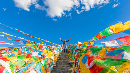 Low angle view of man standing on steps amidst colorful prayer flags