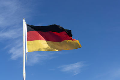 Low angle view of flag against blue sky