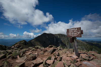 Road sign by mountain against sky