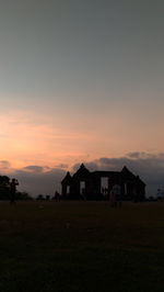 Houses on field against sky during sunset