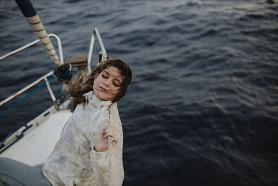 Woman leaning on net while sitting on sailboat during vacation