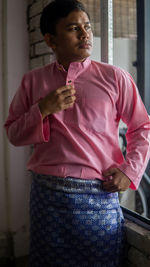 Man looking away while standing on pink indoors