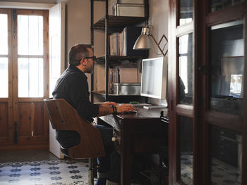 Side view of young man sitting at home