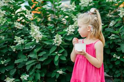 Portrait of smiling young woman standing against plants