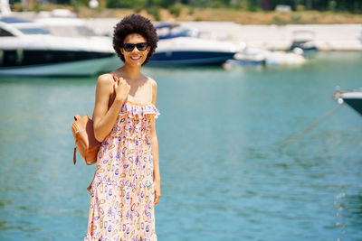 Portrait of young woman standing against lake