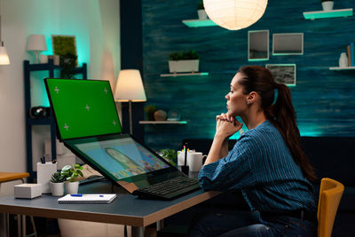 Young woman using phone while sitting on table