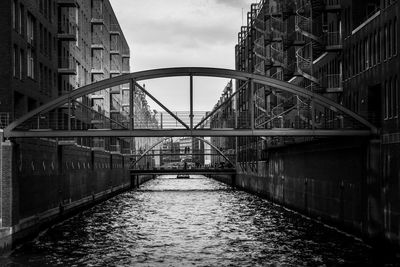 Bridge over river in city against sky