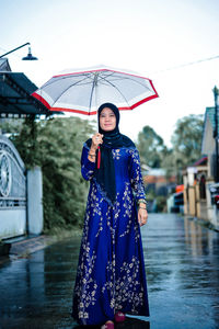 Portrait of woman with umbrella walking on street