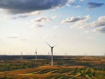 Wind turbines on field against sky