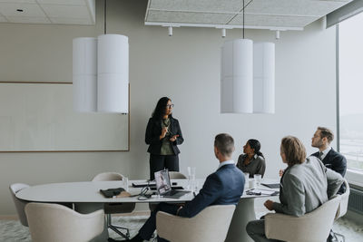 Businesswoman discussing strategy with colleagues in board room during meeting