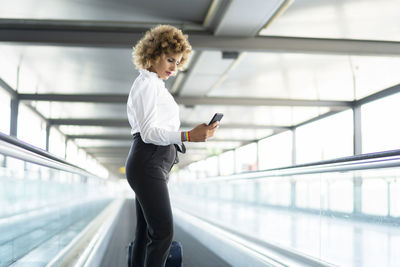 Stewardess in white shirt using her smartphone