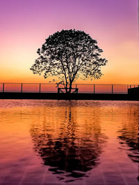 Silhouette tree by sea against romantic sky at sunset