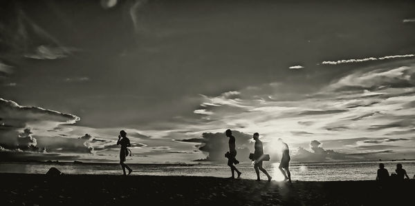 Silhouette people on beach against sky