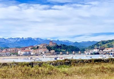 Scenic view of townscape by mountains against sky