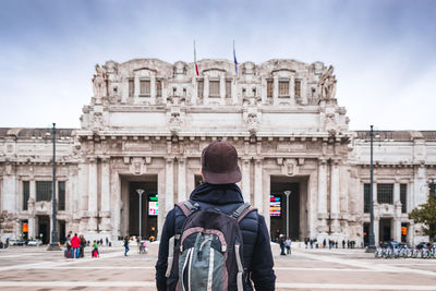 Rear view of woman standing in front of historical building