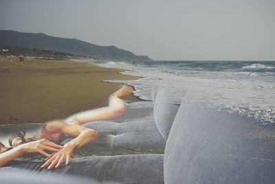 Midsection of shirtless man at beach against sky