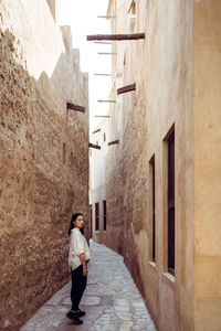 Rear view of man walking on footpath amidst buildings