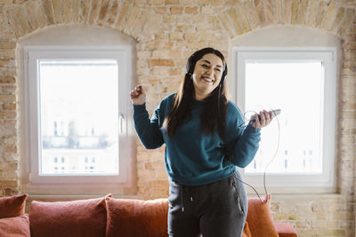 Cheerful woman dancing while listening to music at home