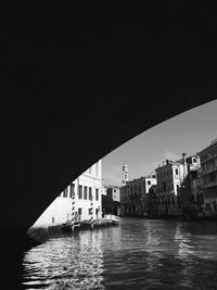 Buildings by river against clear sky