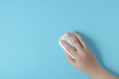 Cropped hand of person against blue background