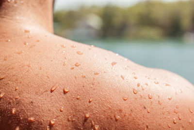 Close-up of water drops on man shoulder during sunny day