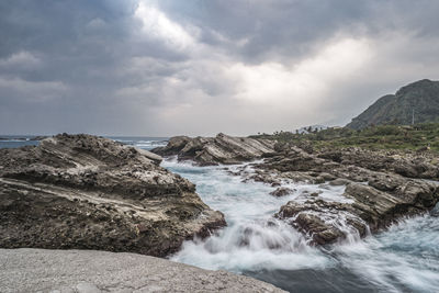 Scenic view of rocks in sea against sky