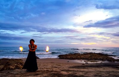 Woman holding firework display at beach during sunset