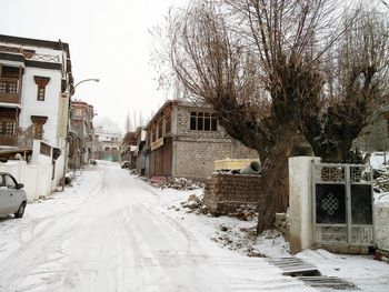 Snow covered road amidst buildings in city