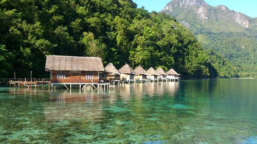 House by lake and trees against mountain