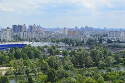 Trees and buildings in city against sky