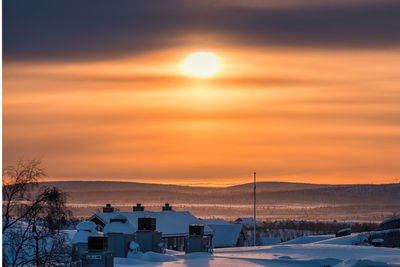 Scenic view of snow covered mountains against orange sky