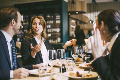 Businesswoman talking while gesturing by coworker in restaurant