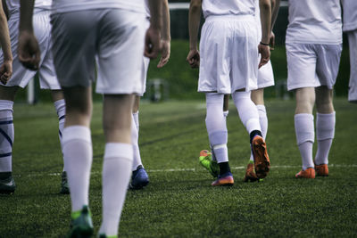 Low section of soccer players walking on field