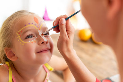 Close-up of mother applying face paint on daughters face at home