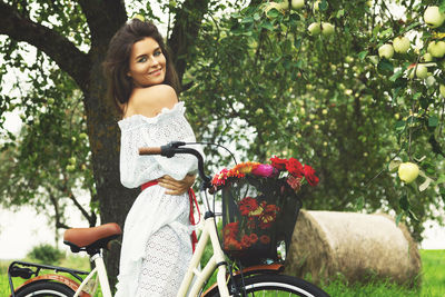 Portrait of young woman riding bicycle on field