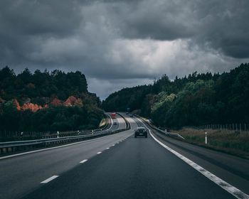 Cars on road against cloudy sky