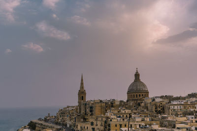 Buildings in city against cloudy sky