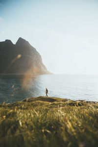 Man walking on land by sea against sky