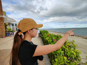 Rear view of woman standing at beach against sky