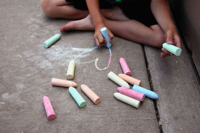 Low section of boy drawing heart shape with chalk on walkway