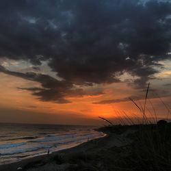 Scenic view of sea against dramatic sky during sunset