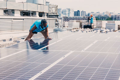 Serious male worker installing modern solar panels while working in industrial area of plant on sunny day