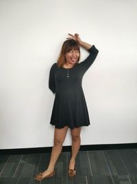 Portrait of a smiling young woman standing against wall