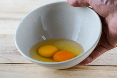 Cropped hand of person holding red chili peppers in bowl on table