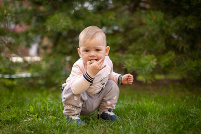 Portrait of cute kid crouching on grass