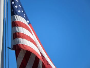 Low angle view of flag against clear blue sky