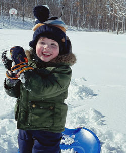 Portrait of boy standing on snow covered field
