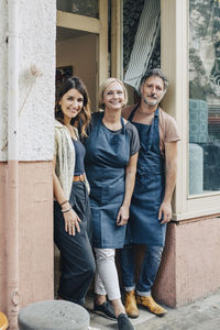 Portrait of smiling male and female upholstery workers standing at workshop entrance