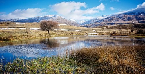 Scenic view of lake by snowcapped mountains against sky