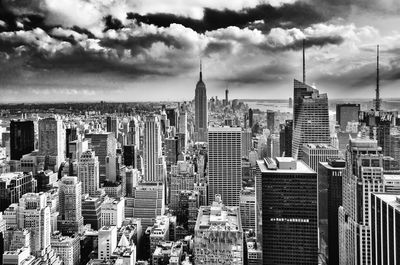 Aerial view of buildings in city against cloudy sky